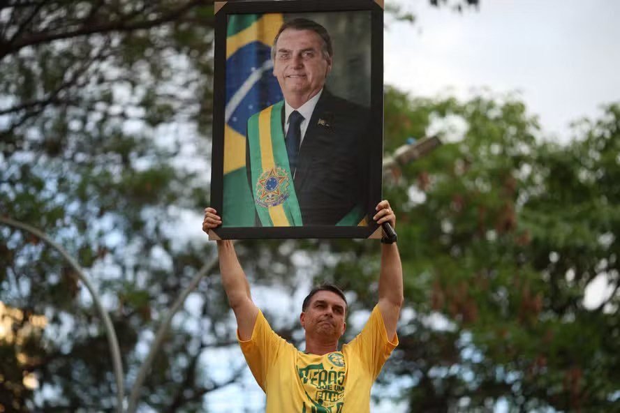 116393925-topshot-brazilian-right-wing-presidential-candidate-flavio-bolsonaro-holds-a-picture-of.avif.jpeg