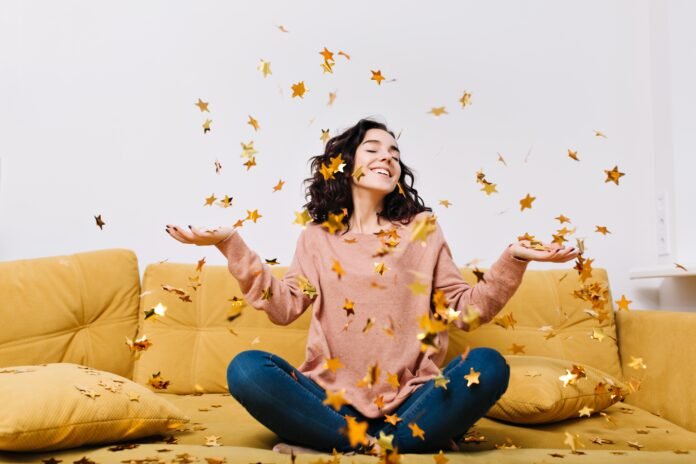 expressing-true-positive-emotions-young-joyful-woman-with-cut-curly-hair-having-fun-falling-tinsels-couch-modern-apartment-home-cosines-joy-smiling.jpg